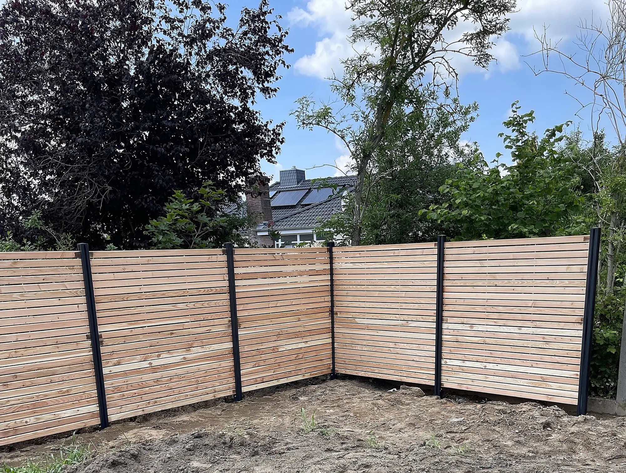Holz-Sichtschutz mit waagerechten Leisten und dunklen Pfosten über Eck