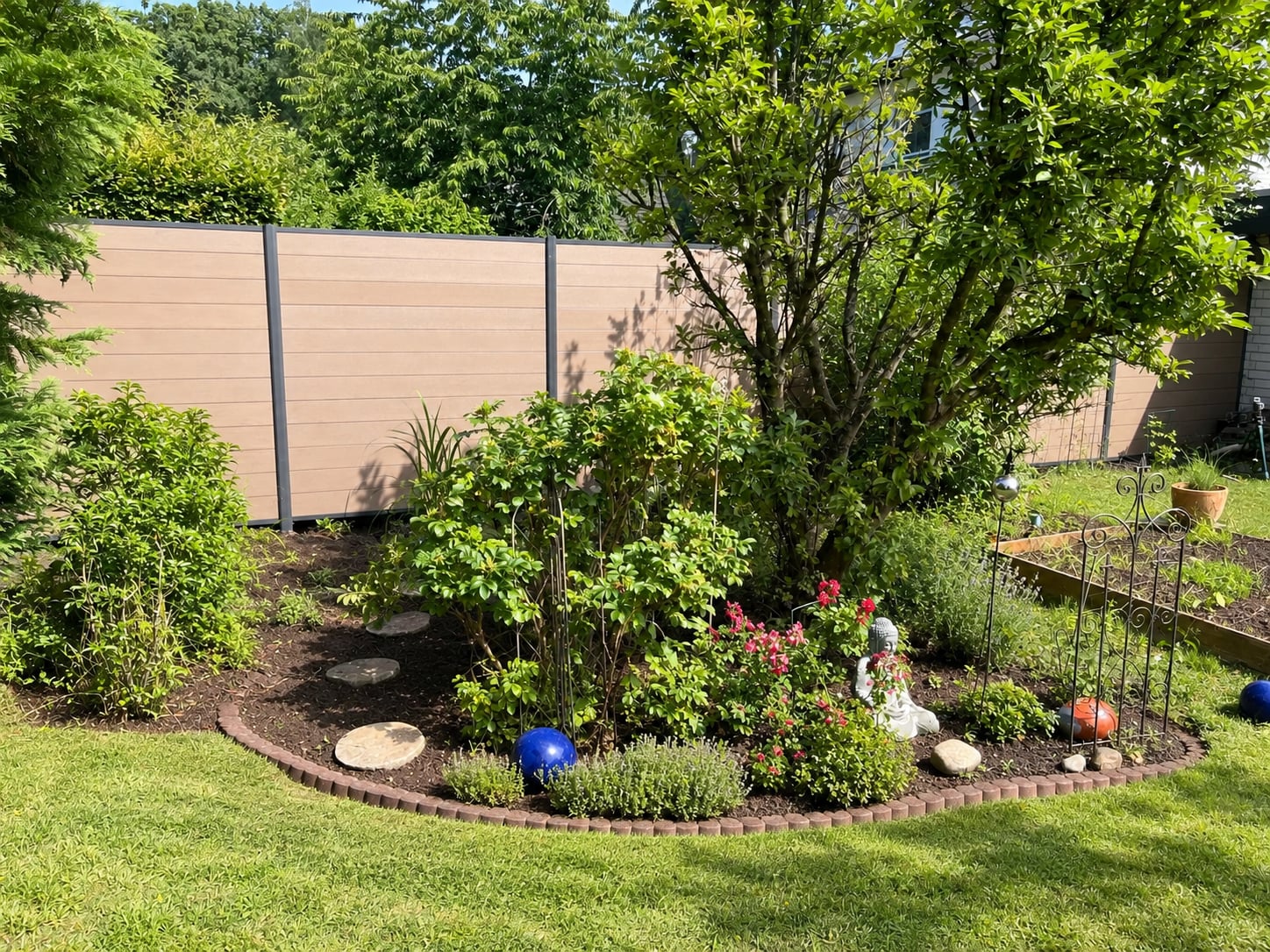 Sandfarbener WPC-Sichtschutz mit grauen Pfosten hinter einem üppig bepflanzten Gartenbeet